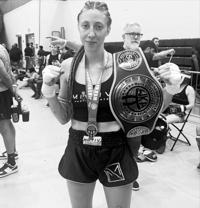 Annika Kahl holding a championship belt after a win